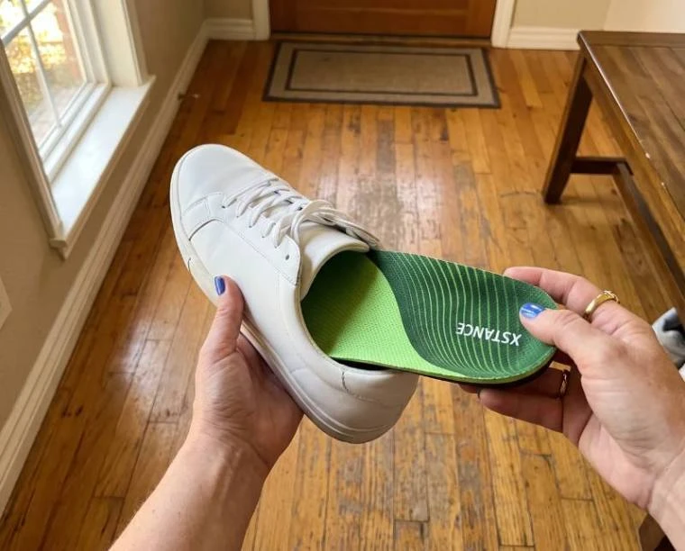 Hands sliding a green XSTANCE insole into a white sneaker